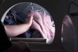 hand in clothing dryer holding pink towel