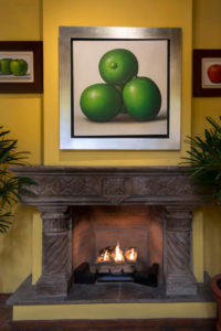 gray fireplace mantel with large painting of green apples above it